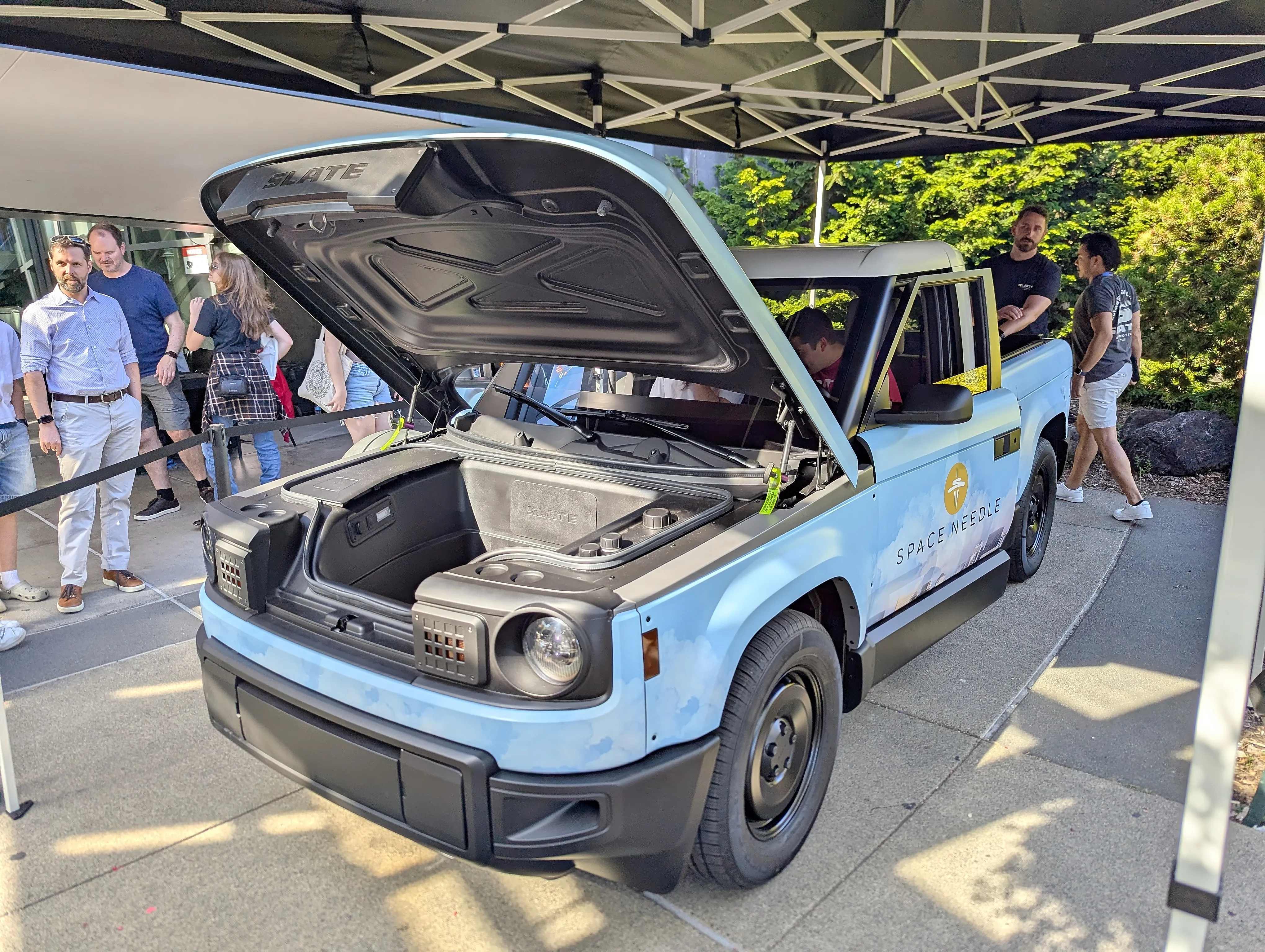 A demonstration Slate Truck in Seattle with its front trunk open, wrapped in a light-blue Space Needle livery